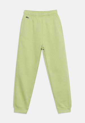 Lys grønn joggebukse med elastisk midjebånd og mansjetter, sidelommer og en liten brodert krokodille-logo nær venstre lomme.