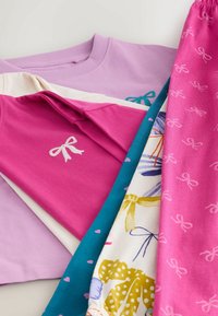 Cinque capi d'abbigliamento: una felpa lilla, una camicia rosa chiaro con un fiocco, un pezzo a fantasia verde acqua, e dei pantaloni rosa a fantasia con fiocchi.
