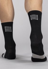 Black athletic socks with a ribbed texture, featuring grey stripes and brand logo at the cuff; ankle height design.