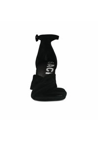 Zwarte suede hoge hak sandaal met een enkelbandje, met een gedraaide voorkant en een vierkante teen, op een platte zool.