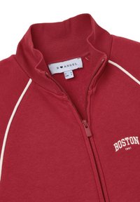 Felpa rossa con zip, colletto a coste, rifiniture bianche e la scritta "BOSTON" ricamata in bianco sul lato sinistro. Etichetta che indica la taglia S.