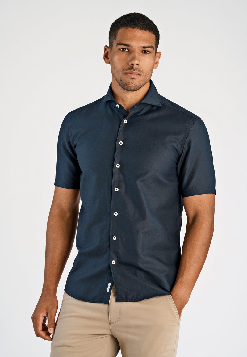 Marineblauwe overhemd met korte mouwen van lichtgewicht stof, met een knoopsluiting aan de voorkant met witte knopen en een eenvoudige kraag, gladde textuur.