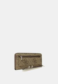 Portefeuille zippé beige avec un motif monogramme, doté d'une texture lisse, d'une sangle pour poignet et d'un accent blanc contrastant sur le côté.