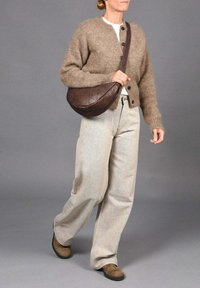 Cardigan de punto marrón con seis botones, pantalones de pierna ancha beige y bolso cruzado marrón. Textura suave y corte relajado en todo.