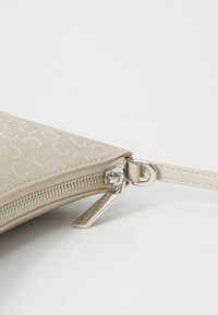 Borsa a clutch beige con zip, motivo impresso, hardware in argento e design piatto. Dotata di un manico per il polso per un trasporto facile.