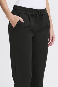 Fekete színű jogging nadrág elasztikus derékrésszel, húzózsinóros megkötéssel és oldalzsebekkel. Sima tapintású, szűkített szabású és letisztult dizájnú.