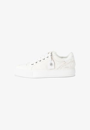 Witte lage sneaker met dikke zool, veters aan de voorkant, gestructureerde stof en een merklabel dat aan het zijoogje hangt.