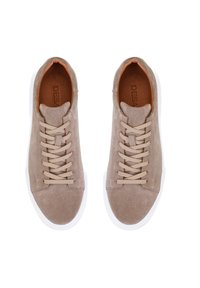 Baskets en daim beige avec des semelles en caoutchouc blanches, dotées de lacets beiges et d'un intérieur marron avec le nom de la marque en relief. Pas de motifs ni d'accents.