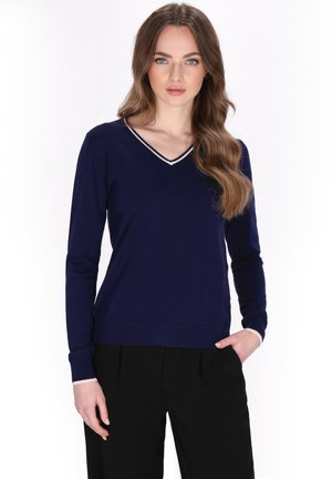 Pullover a maglia blu navy con scollatura a V e bordo beige a contrasto lungo il collo e i polsi; maniche lunghe e silhouette aderente.