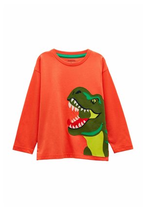 Svetlooranžové tričko s dlhým rukávom s veľkou zelenou karikatúrnou hlavou dinosaura, otvorenou tlamou zobrazujúcou zuby, potlačené na prednej pravej strane.