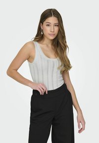 Ljusgrå stickad linne med vertikala ränder, kombinerat med höga svarta byxor. Outfiten har en avslappnad passform och en mjuk textur.