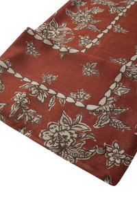 Tessuto rosso con motivi floreali bianchi e grigi. Presenta una superficie текстurizzata e un piccolo etichetta metallica in un angolo.