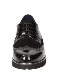 Zwarte leren oxford schoen met een gladde patina afwerking en suède accenten, gedetailleerde perforaties en een stevige rubberen zool.