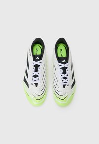 Chaussures de football blanches et noires avec des accents vert néon, surface texturée, design incurvé et logo à trois bandes proéminent sur le côté.