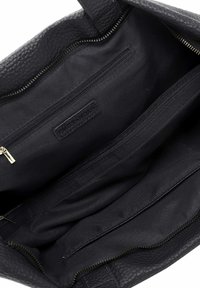 Black leather tote bag interior, featuring multiple compartments, a zippered pocket, and a brand label, all with a soft fabric lining.