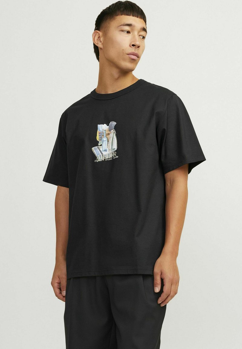 Camiseta de algodón negra de corte relajado, con un estampado gráfico colorido de botellas en la parte delantera y un escote redondo.