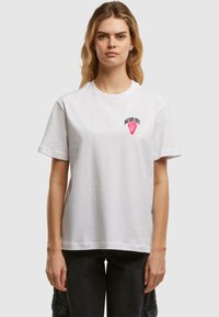 Hvit bomull T-skjorte med rund hals, korte ermer, og trykt rosa logo design på brystet. Rett snitt, glatt tekstur.