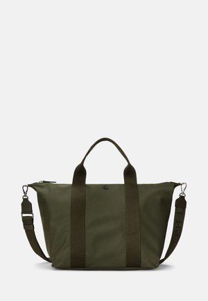 Grand sac fourre-tout vert foncé avec deux poignées et une bandoulière ajustable, sur un fond clair uni.