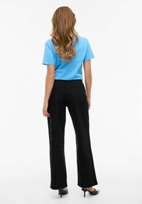 Jasnoniebieska koszulka z krótkim rękawem w połączeniu z czarnymi, szerokimi spodniami z wysokim stanem, wyposażonymi w tylne kieszenie i gładką teksturę.
