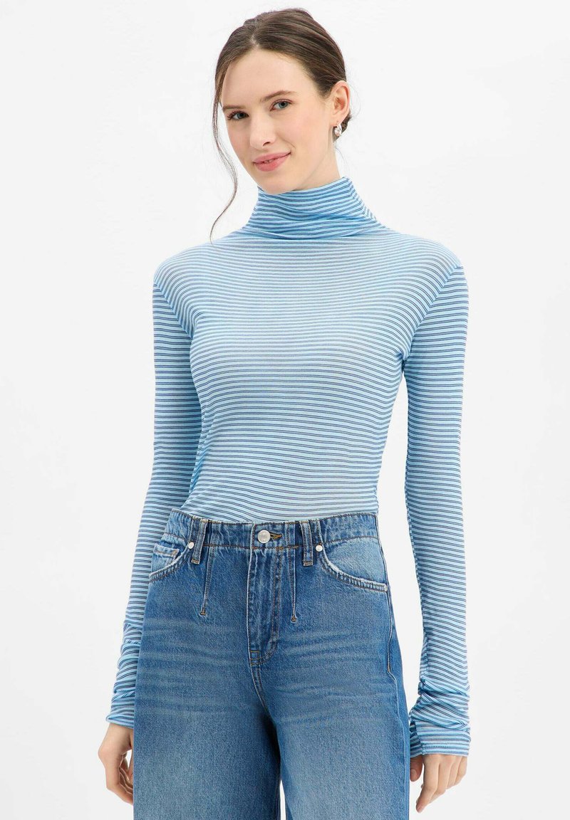 Col roulé à manches longues rayé bleu et blanc, coupe ajustée, en tissu doux, assorti à un jean denim taille haute.