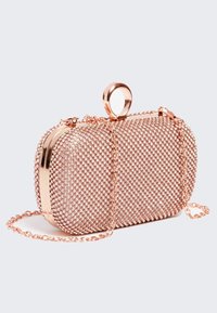 Kabelka ve růžově zlaté barvě s třpytivými rhinestonovými detaily, oválného tvaru, kovový rám, řetízkový popruh na nošení a kulatý akcent na vrchu pro otevírání.