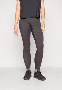 Dark gray leggings made from stretchy material, fitted design, featuring textured side panels and paired with a loose black top and black shoes.
