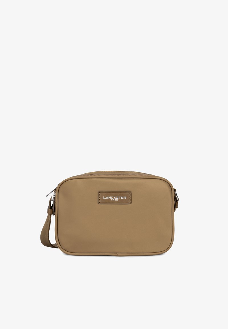 Sac bandoulière synthétique beige avec une fermeture éclair, de forme rectangulaire, et une étiquette décorative arborant "Lancaster Paris" en couleur argent.