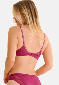 Magenta lingerie set met een kant achterkant, verstelbare bandjes en een gladde satijnen afwerking. Inclusief bijpassende bikini-onderbroek met kantafwerking.