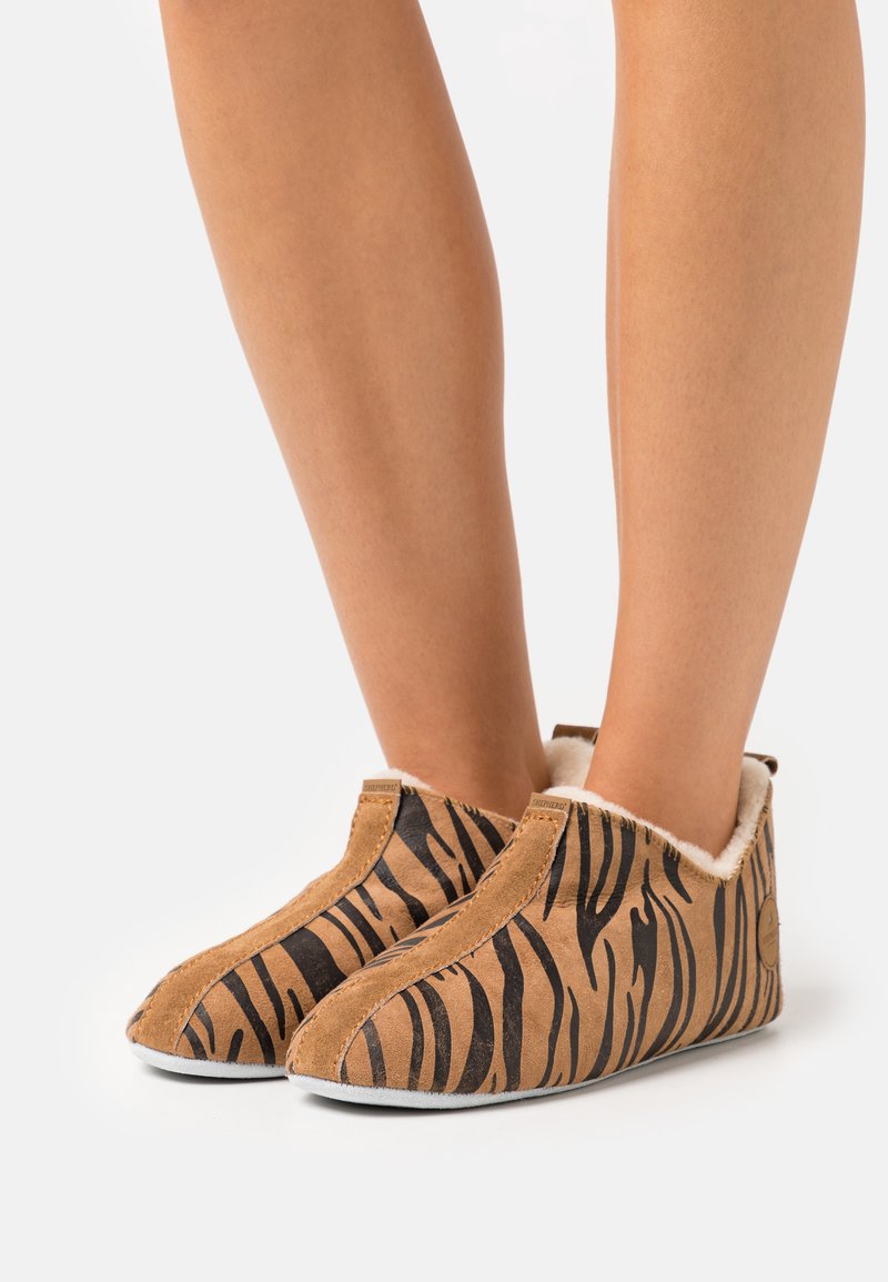 Tan slippers med svart tigerstripemønster, myk innvendig fôr og rund tå, med lav skåring og slip-on design.
