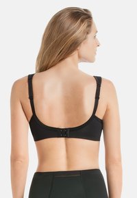 Schwarzer BH mit verstellbaren Trägern und einem runden Rücken design. Ausgestattet mit einem Haken- und Ösenverschluss mit drei Befestigungen. Glatte Stofftextur.