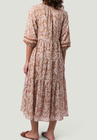 Hnědá a bílá midi šaty s vzorem paisley, s třičtvrtečními rukávy, elastickým pasem a nabranou sukní. Lehčí materiál, volný design.