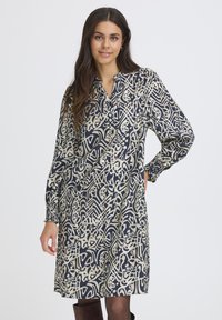 Langärmliges Kleid in Marineblau mit cremefarbenem abstraktem Muster, mit einem kragenförmigen Ausschnitt und gerafften Manschetten, aus leichtem Stoff gefertigt.