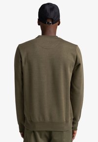 Felpa verde oliva con polsini e orlo a costine, dotata di scollatura rotonda e texture morbida. La vista posteriore mostra cuciture minime e linee pulite.