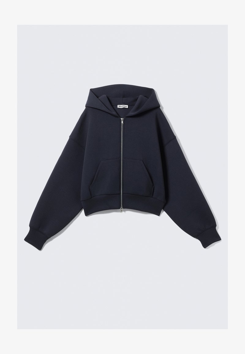 Sweat à capuche court bleu marine en tissu doux, doté d'une fermeture éclair à l'avant, d'une capuche surdimensionnée et de deux poches latérales avec poignets et ourlet côtelés.