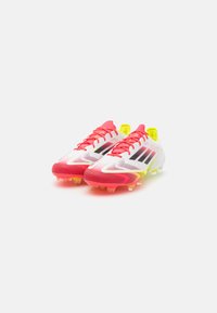 Cristianul de fotbal roșu și galben cu un superior din plasă, dungi negre și o talpă texturată. Prezintă accente strălucitoare și un design aerodinamic.