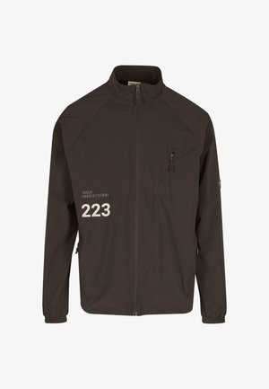 Tumedas pruunis tõmblukuga jope, millel on kõrge krae, tõmblukuga rinnatasku, elastsed mansetid ja valge "223" tekst vasakul rinnal.