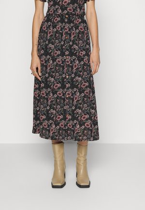 Saia midi preta com padrão floral em rosa e verde, com detalhes em botão, combinada com botas de tornozelo bejes.