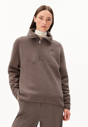 Bruine fleece pullover met een half-rits kraag, gestructureerd oppervlak en een subtiele logo op de borst. Heeft een relaxte fit en lange mouwen.