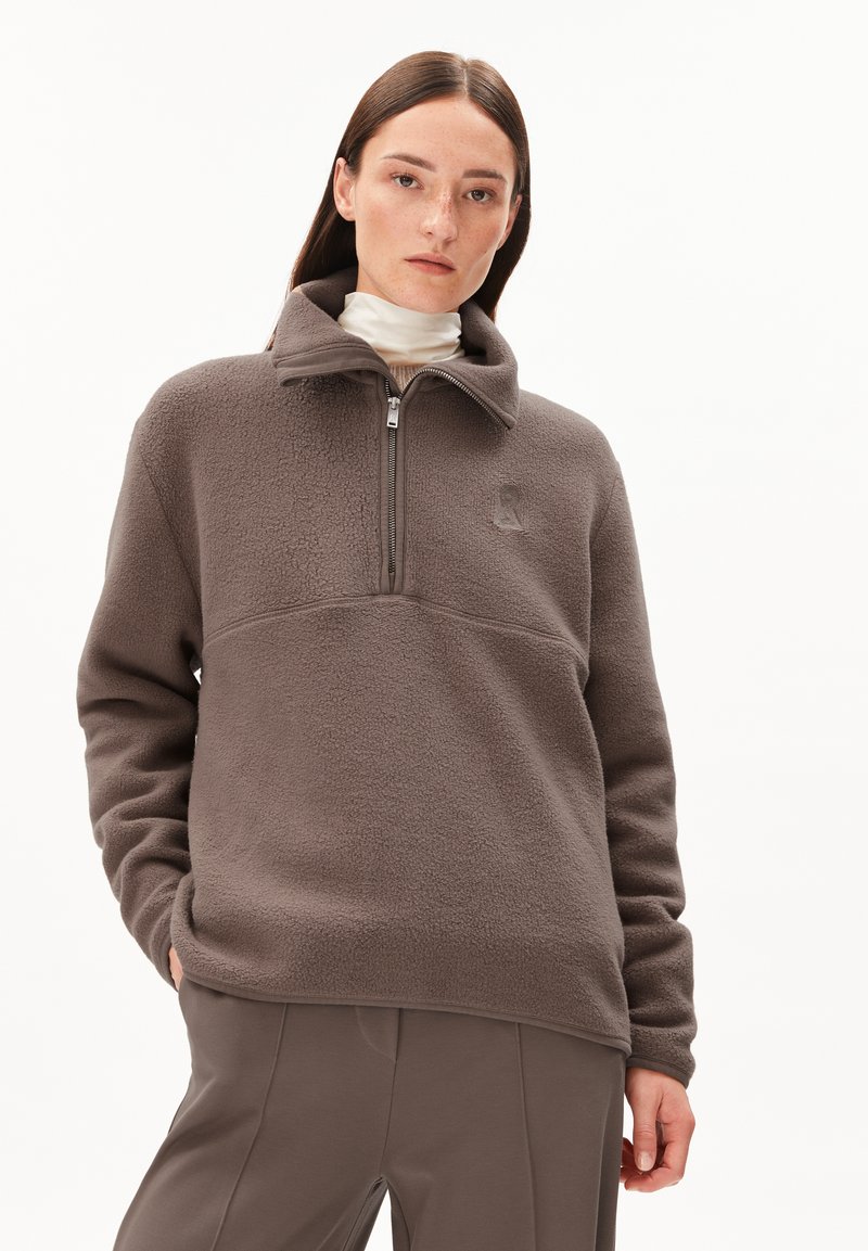 Bruine fleece pullover met een half-rits kraag, gestructureerd oppervlak en een subtiele logo op de borst. Heeft een relaxte fit en lange mouwen.