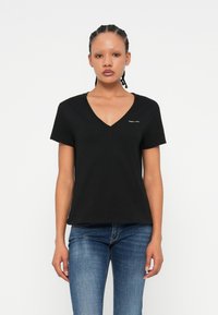 T-shirt nera a V in cotone morbido, con maniche corte e taglio dritto. Piccolo dettaglio del logo nella zona sinistra del petto.