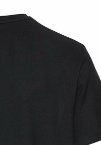 Sort T-shirt med rund hals, korte ærmer og et struktureret stof. Sømmen er synlig på skulderen og halsudskæringen.