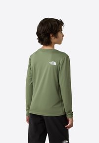 Cămașă cu mâneci lungi, verde măsliniu, dintr-un material texturat. Are un logo pe spate. Purtați cu pantaloni negri, cu o croială lejeră.