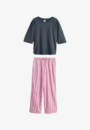Mørkegrå kortærmet t-shirt med rund hals kombineret med løse lyserøde bukser med lodrette sorte striber og snørebånd i taljen.