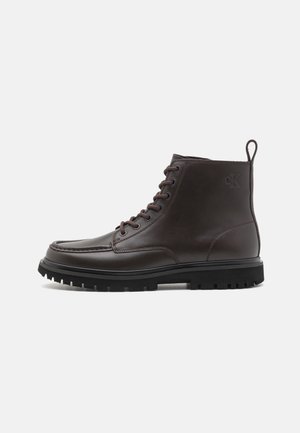Brown leather ankle boots with a smooth finish, round toe, lace-up front, and rugged black sole featuring deep treads and a pull tab.