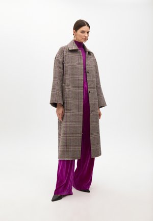 Plaid oversized coat with a collar, textured fabric in shades of grey, purple, and white. Layered over a purple turtleneck and trousers.