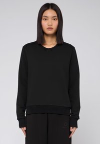 Svart sweatshirt med långa ärmar, ribbad halsringning och mudd, slät textur. Har en minimalistisk design utan synliga logotyper eller mönster.