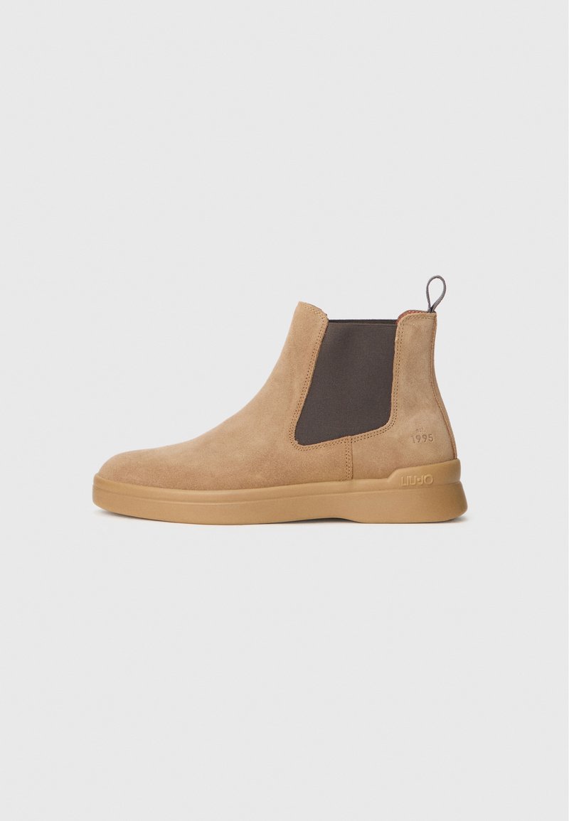 Stivaletti alla caviglia in suede beige con pannelli laterali elasticizzati e suola in gomma. Presentano un pratico pull tab e un marchio in rilievo sul tallone, con una texture liscia.