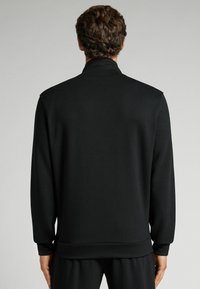 Svart sweatshirt, mjukt tyg, hög krage, långa ärmar och ribbade muddar och nederkant, med en slät, odekorerad design.