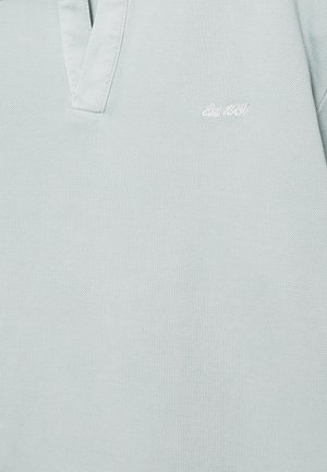 Világosszürke galléros póló rövid gallérral és kis fehér hímzéssel a mellkason, amelyen az "Est. 1921" felirat olvasható.