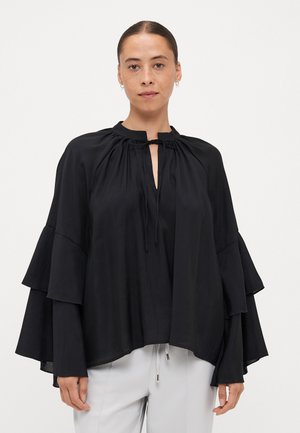Black blouse with layered, bell-shaped sleeves. Features a round neckline with a tie, crafted from a smooth, lightweight fabric.